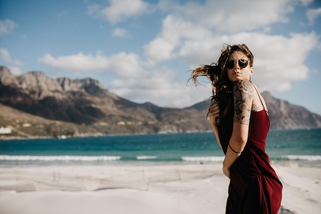 Zijkant van een jonge vrouw die op het strand staat tegen de lucht