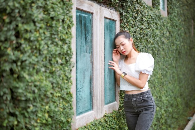 Foto zijkant van een jonge vrouw die tegen de muur staat