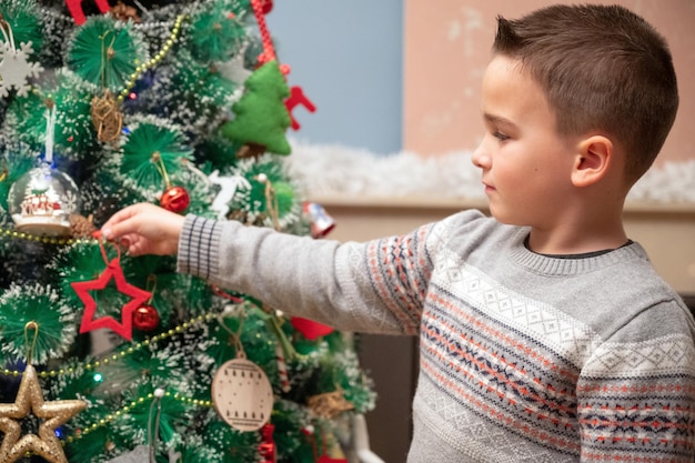 Zijkant van een jongen die een kerstboom siert