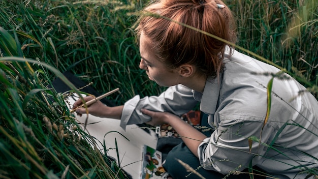 Foto zijkant van een jongen die een mobiele telefoon gebruikt in het gras