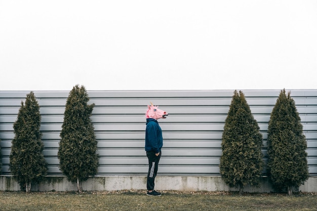 Foto zijkant van een man met een masker bij de muur