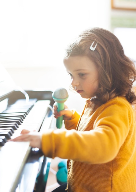 Foto zijkant van een meisje dat thuis piano speelt