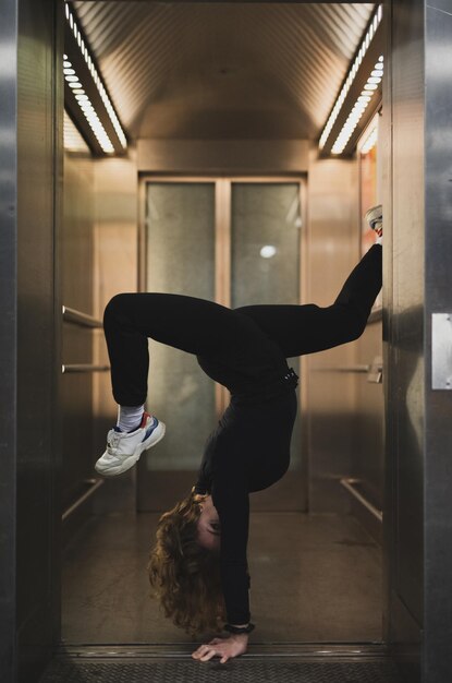 Foto zijkant van een vrouw die handstand doet bij de deur