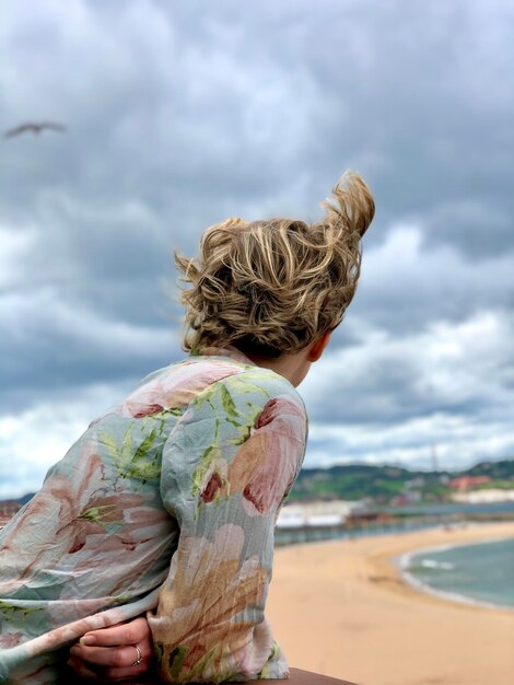 Foto zijkant van een vrouw die naar de zee kijkt tegen de lucht