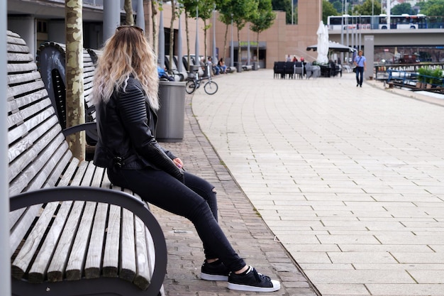 Zijkant van een vrouw die op een bankje in de stad zit