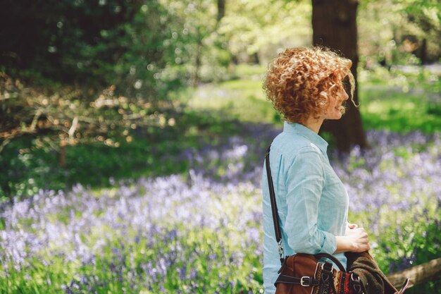 Foto zijkant van een vrouw die op een zonnige dag door planten in het bos loopt