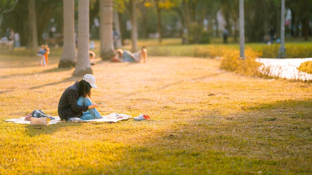 Zijkant van een vrouw die op het gras in het park zit