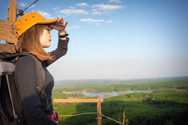 Foto zijkant van een vrouw die op het veld tegen de lucht staat