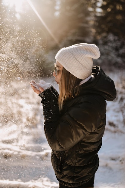 Zijkant van een vrouw die sneeuw blaast terwijl ze in de winter buiten staat