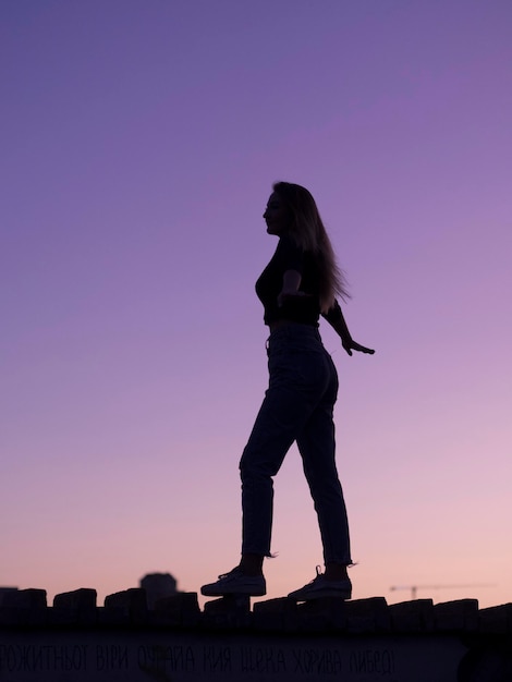 Zijkant van een vrouw die tijdens de zonsondergang tegen een heldere lucht staat