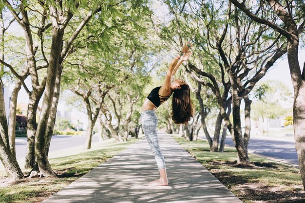 Zijkant van een vrouw die yoga doet en zich strekt in een park