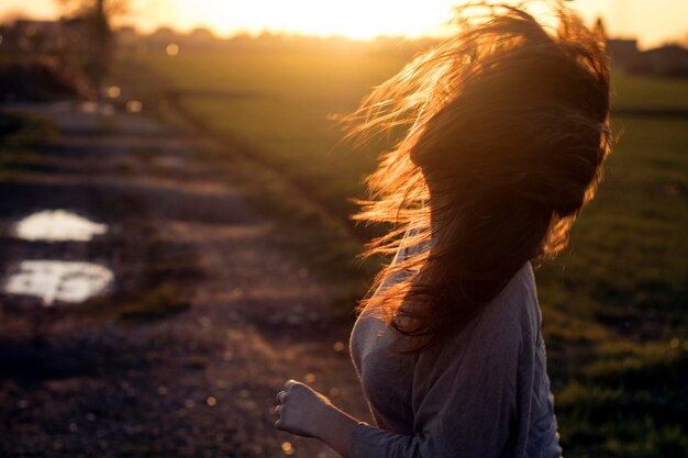 Zijkant van een vrouw met losgeknipt haar bij zonsondergang