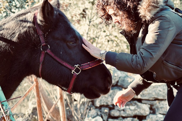 Foto zijkant van jonge vrouw met paard