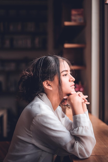 Zijkantbeeld van een bedachtzame vrouw die in een koffieshop zit