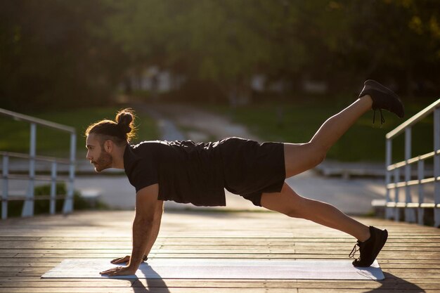 Zijkantbeeld van een fitnessman die plankbeen verhoogt buiten