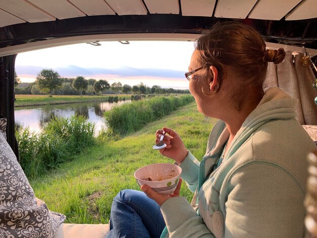 Foto zijkantbeeld van een jonge man die eten eet bij de rivier