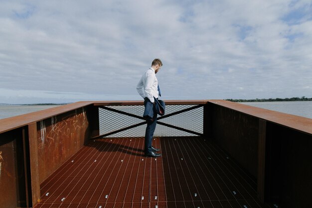 Foto zijkantbeeld van een man die bij de zee staat tegen een bewolkte lucht