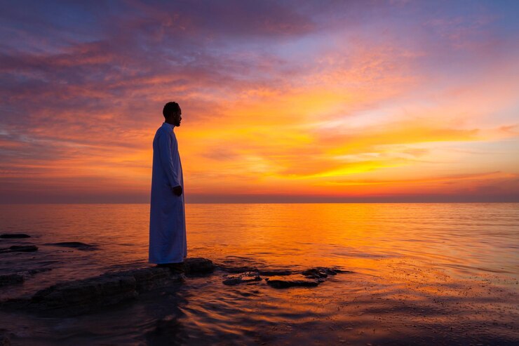 Foto zijkantbeeld van een man die tijdens de zonsopgang op het strand tegen de lucht staat