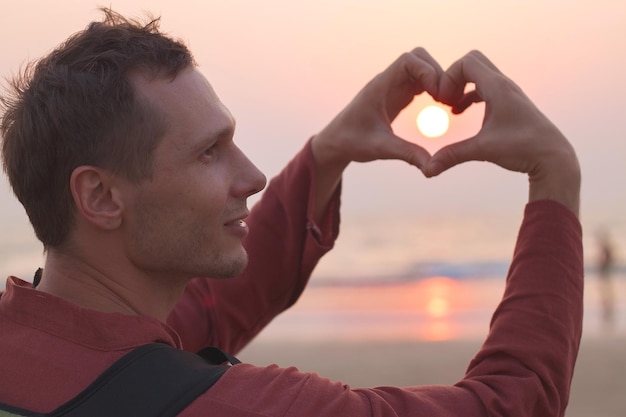 Foto zijkantbeeld van een volwassen man die een hartvorm maakt tegen de hemel tijdens de zonsondergang