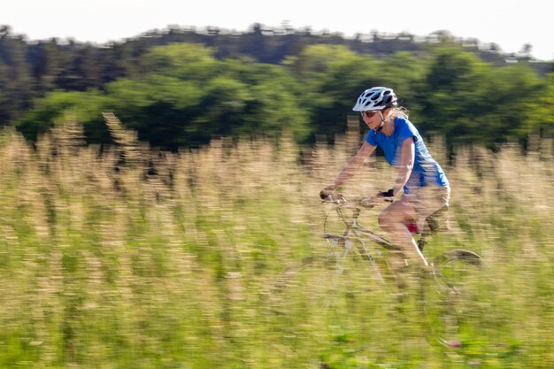 Foto zijkantbeeld van een vrouw die in het midden van een veld fietsen