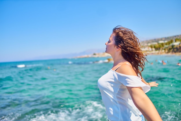 Zijkantbeeld van een vrouw met uitgestrekte armen die tegen de heldere lucht op het strand staat