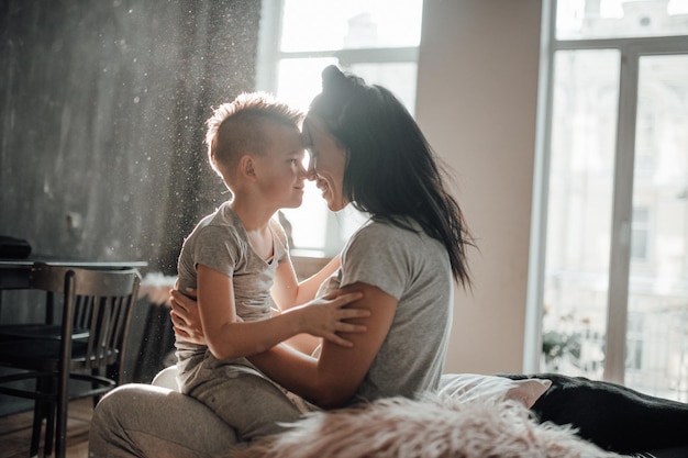 Foto zijkantbeeld van moeder en dochter die op het raam zitten