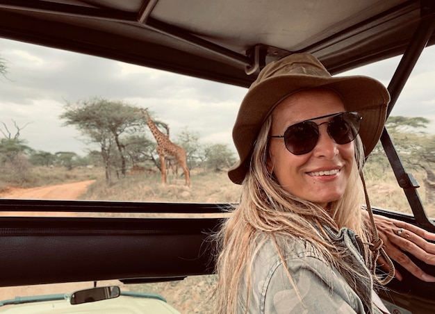 Foto zijkantportret van een glimlachende vrouw in een safarivoertuig in een nationaal park