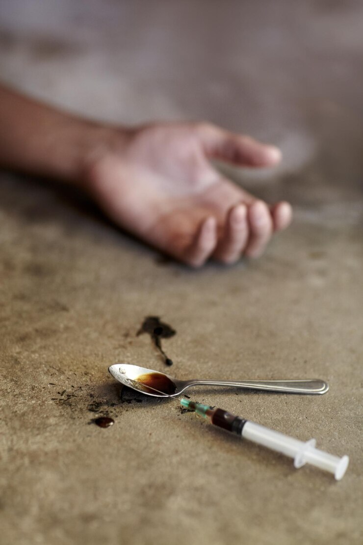 Foto zijn laatste high close-up shot van een slappe arm van een drugsverslaafde met drugsparafernalia ernaast