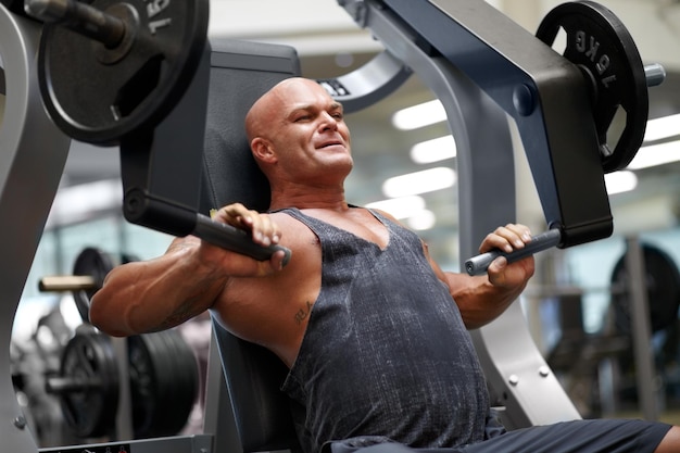 Zijn spiermassa opbouwen, shot van een mannelijke bodybuilder met fitnessapparatuur in de sportschool
