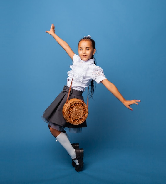 Zijprofielfoto van schoolmeisjesmeisje, gelukkige positieve glimlach, springen, lopen, geïsoleerd op blauwe achtergrond