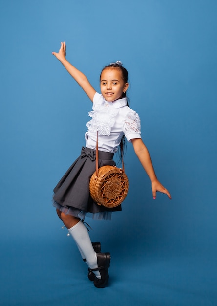 Zijprofielfoto van schoolmeisjesmeisje, gelukkige positieve glimlach, springen, lopen, geïsoleerd op blauwe achtergrond