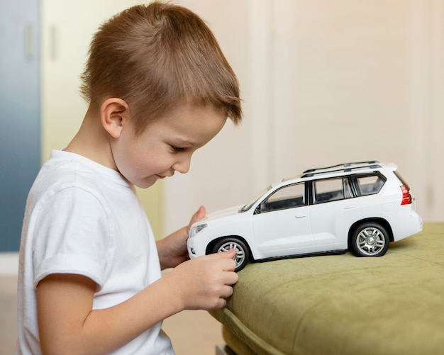 Zijwaarts jongen speelt met een witte auto