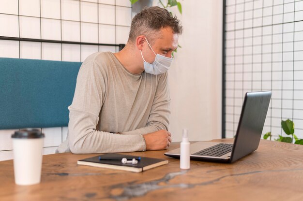 Foto zijwaarts moderne man met medische masker werken