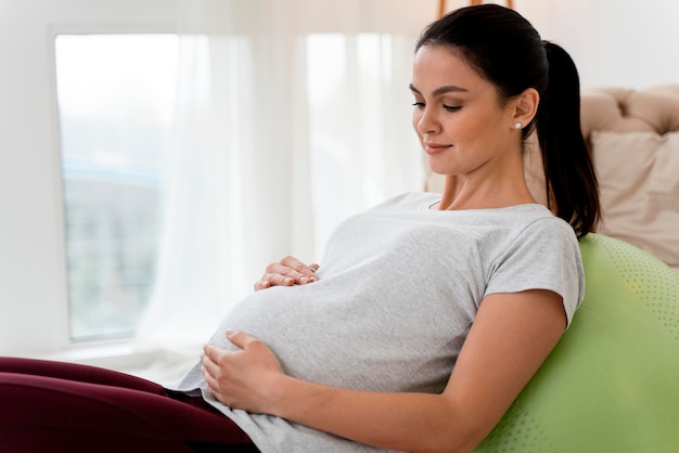 Foto zijwaarts zwangere vrouw die op geschiktheidsbal uitoefent