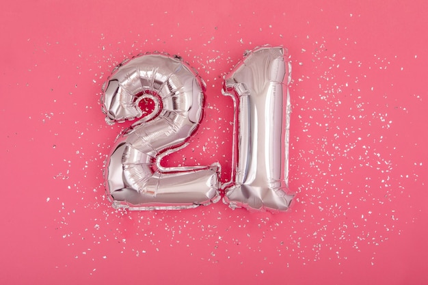 Zilveren ballon in de vorm van nummer één 21 roze achtergrond