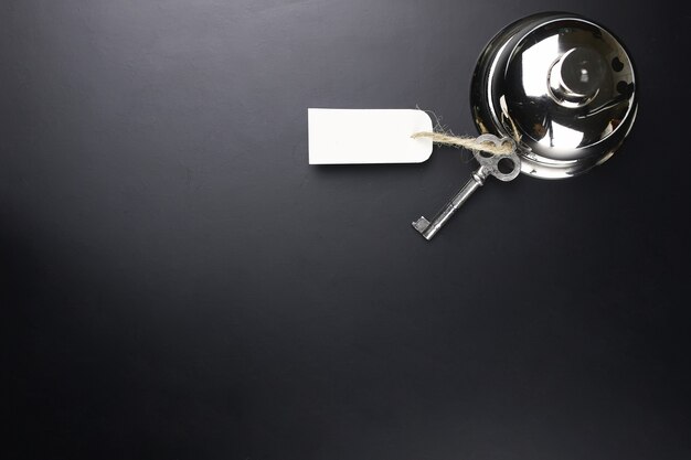 Zilveren bel en de sleutel bij de receptie in het hotel op een zwarte achtergrond