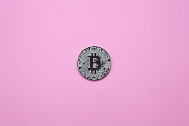 Zilveren bitcoin op een duizendjarige roze achtergrond. bovenaanzicht. minimalisme. horizontale oriëntatie. plat leggen