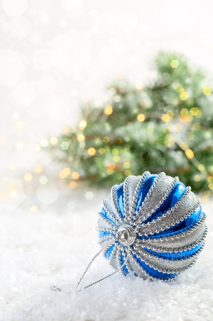 Zilveren en blauwe kerstballon op een met sneeuw bedekte tafel