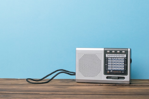 Zilveren retro radio op een houten tafel op een blauwe achtergrond.