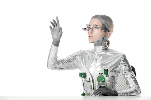zilveren robot zit aan tafel en raakt iets geïsoleerd aan wit toekomst technologie concept