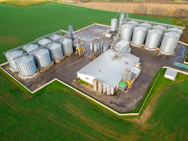 Zilveren silo's op agro-fabriek voor verwerking, drogen, reinigen en opslag van landbouwproducten, meel, granen en graan Een drone vliegen over ijzeren vaten graan quadcopter foto