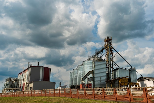 Foto zilveren silo's op agro-fabriek voor verwerking drogen reiniging en opslag van landbouwproducten meel granen en graan grote ijzeren vaten graan graanschuurlift