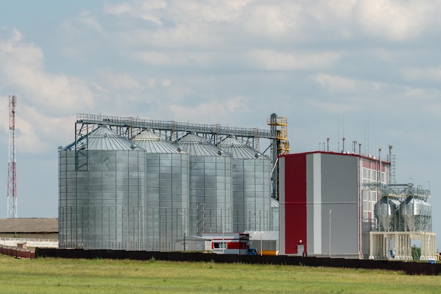 Foto zilveren silo's op agro-fabriek voor verwerking drogen reiniging en opslag van landbouwproducten meel granen en graan grote ijzeren vaten graan graanschuurlift