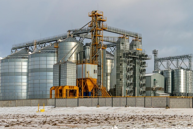 Zilveren silo's tegen de blauwe lucht in de winter Graanopslag in de winter bij lage temperaturen Productie voor verwerking droogreiniging en opslag van landbouwproducten meel granen en graan