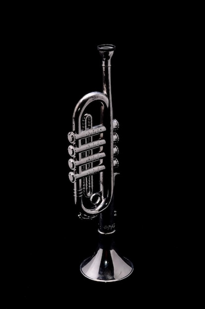 Zilveren vintage speelgoedtrompet op een zwarte achtergrond