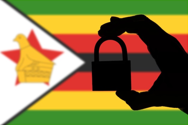 Zimbabwe veiligheid Silhouet van hand met een hangslot boven de nationale vlag