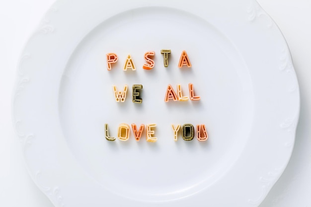 Zin PASTA WE ALL LOVE YOU van droge veelkleurige pasta op een wit bord