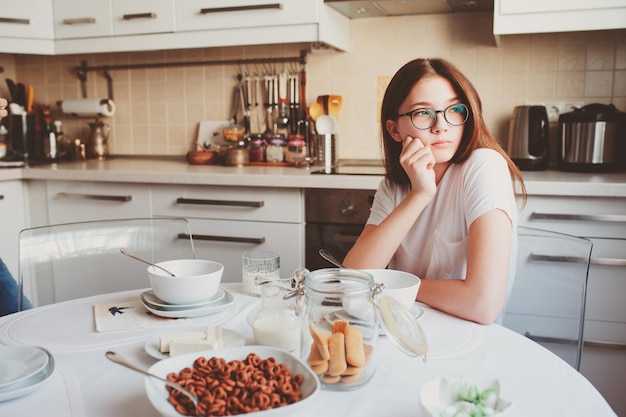 Zinnige vrouw zit aan tafel in de keuken.
