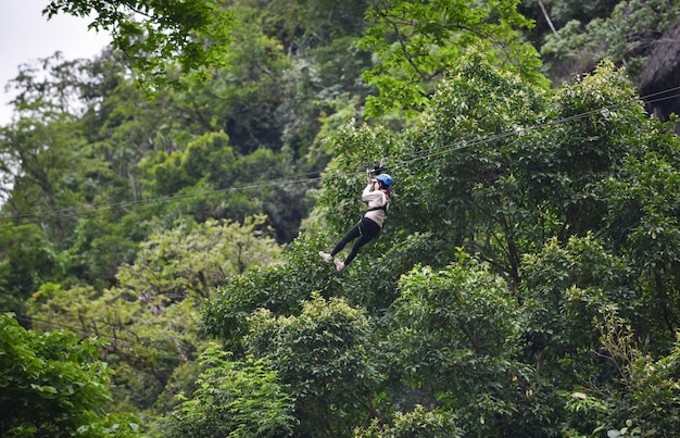 vangviengラオスの森の中の大きな木にぶら下がっているジップラインエキサイティングなスポーツアドベンチャーアクティビティ