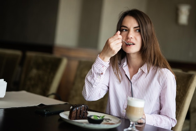 zit binnen in het café-restaurant van de coffeeshop en eet chocolade brownie-dessertcake